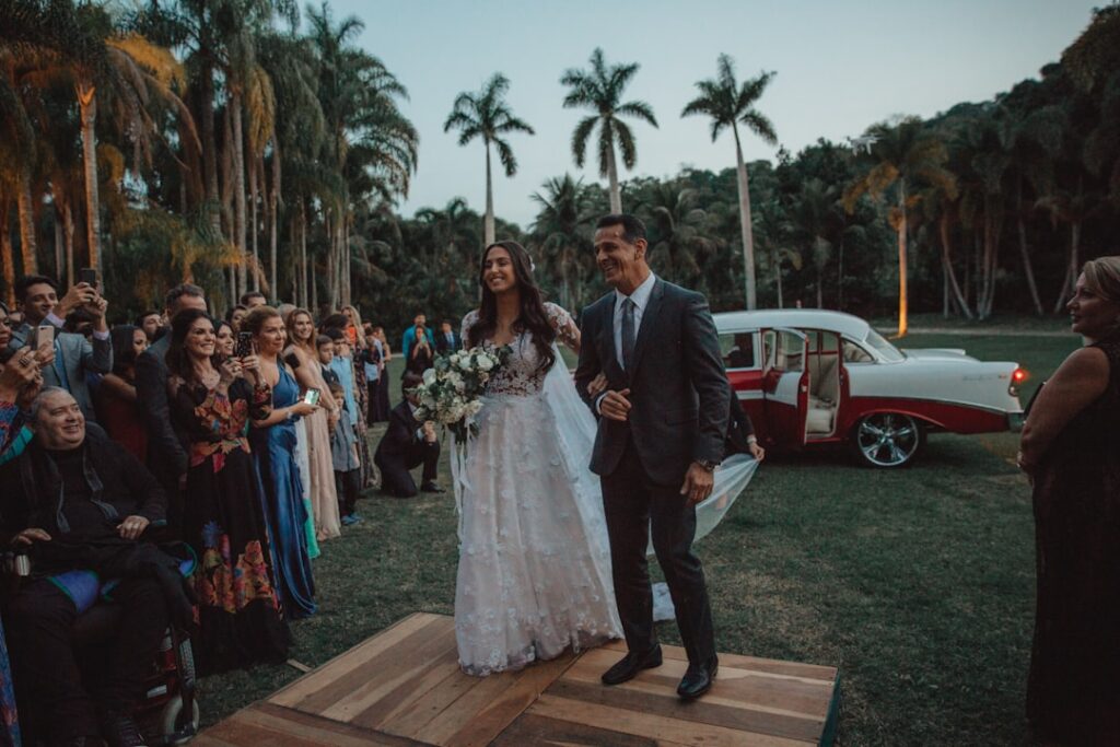Bride and groom arriving at their wedding ceremony venue with a classic car in the background