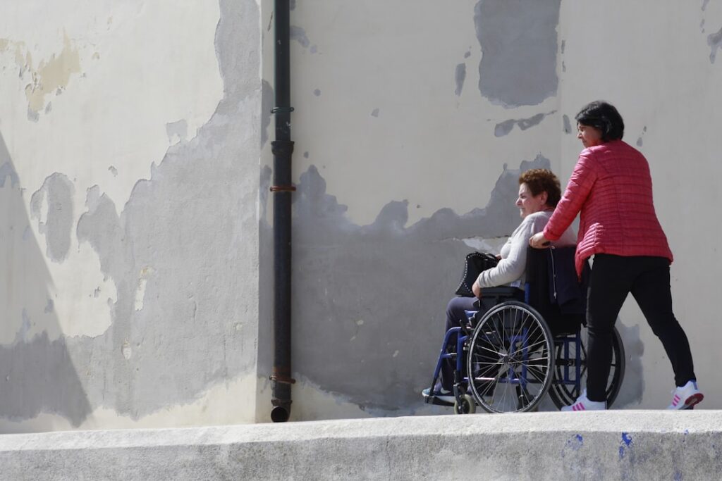 A person in a wheelchair being assisted outdoors, illustrating dignified wheelchair transport in Dorset