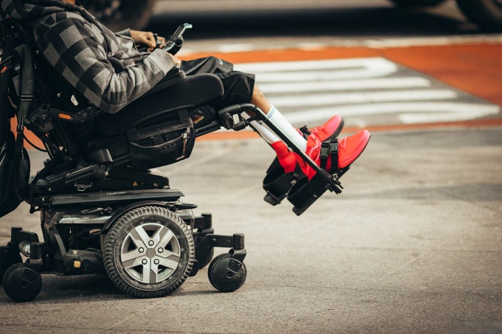 A powered wheelchair user at a street crossing, illustrating everyday local travel for wheelchair users in urban areas