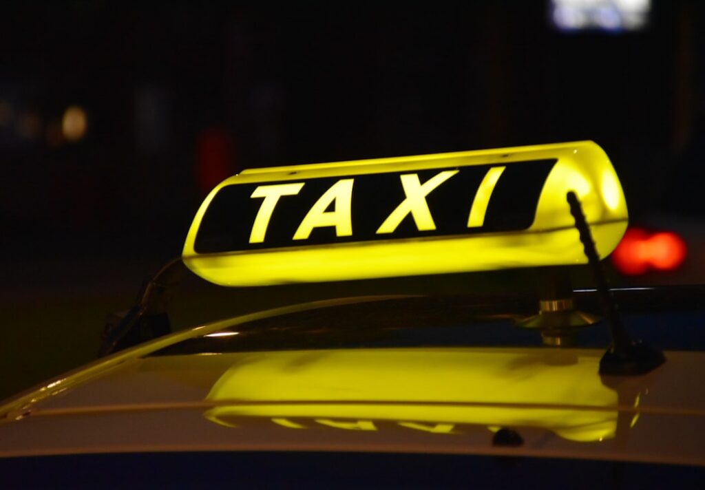 Illuminated taxi sign on a licensed cab at night — fixed fare taxi service
